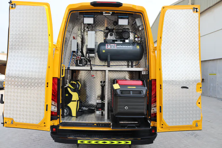 Both rear doors open showing an air compressor, pressure washer and generator secured inside the body