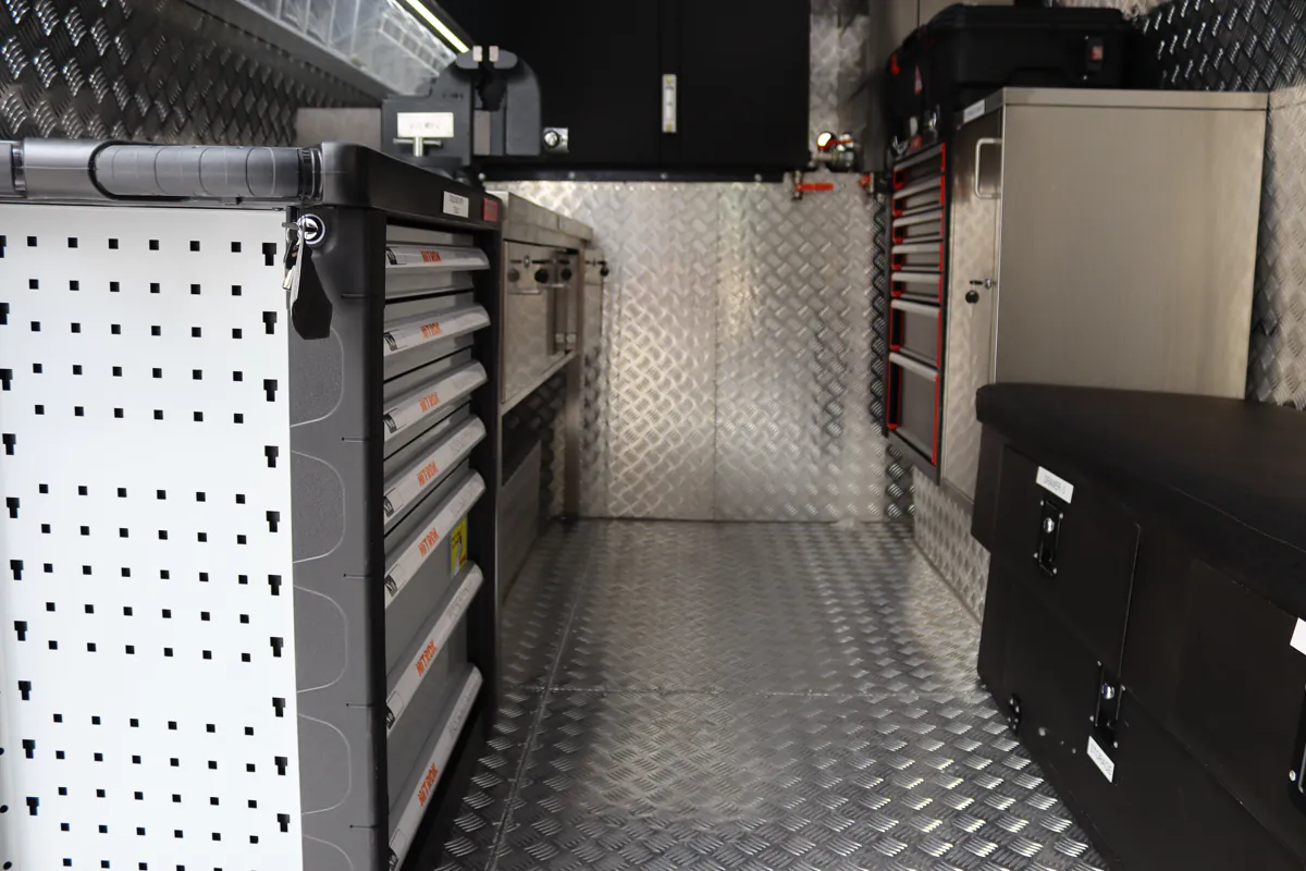 Perforated shadow board panel fitted along the cabin wall beside stacked tool drawer units